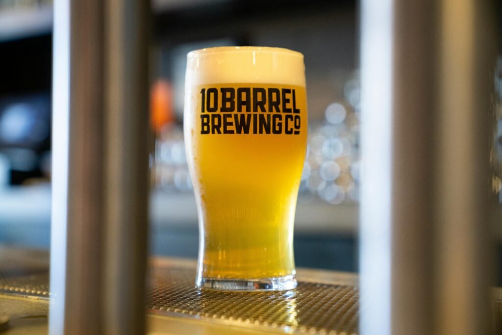 A crisp, cold pint of craft beer with foam, showcasing brewery branding in a bar setting.