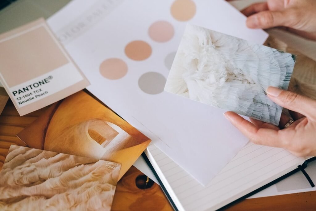 Hands holding Pantone swatches and textured cards for design inspiration.