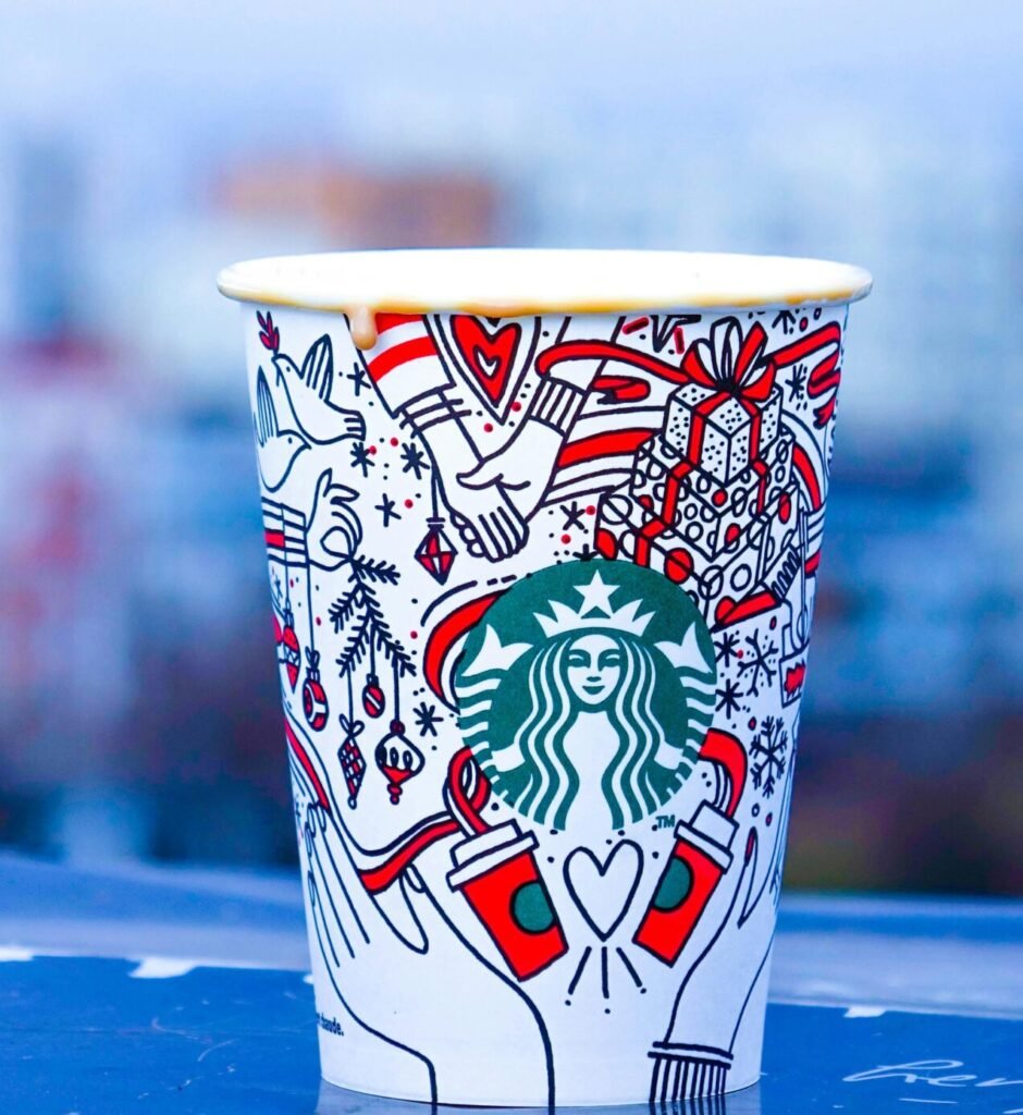 Colorful Starbucks cup against an urban backdrop with blurred city view.